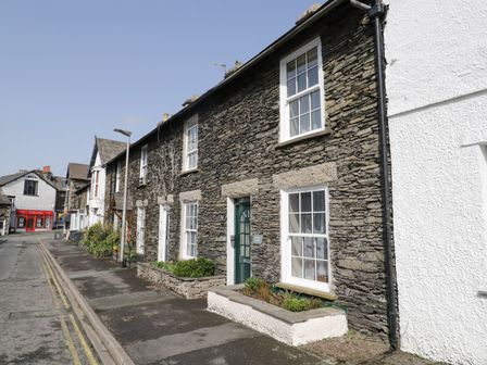 A street view of stone cottages with white window frames and a green door at Myrtle Cottage in Windermere