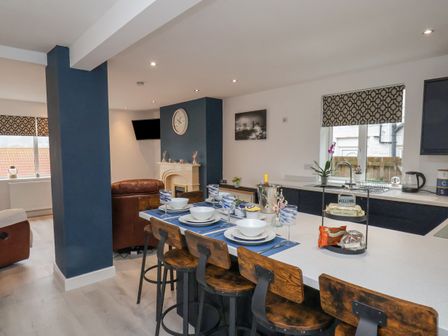 A kitchen and dining area with a white countertop and wooden bar stools at Wobble Pops in Whitby