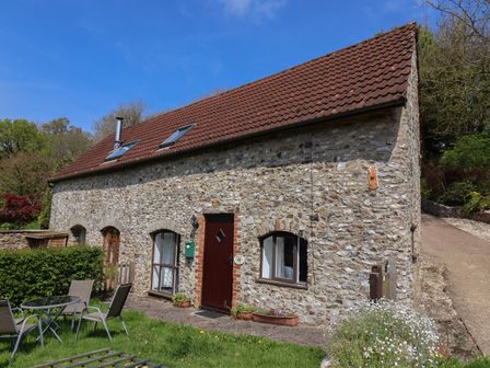Stone cottage with red tiled roof and skylights garden table and chairs on lawn at Butterton Cottage in Combe Raleigh near Honiton