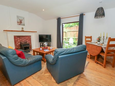A living room with two blue armchairs facing a wooden coffee table and a fireplace with a mounted picture at Coldharbour Farm Bungalow Annexe Coldharbour near Wareham