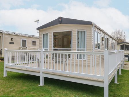 A mobile home with a white fenced deck and outdoor chairs at No 3 Foxburrow Hang in Belton