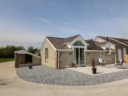 A single story house with patio furniture and potted plants at Y Felin in Caernarfon