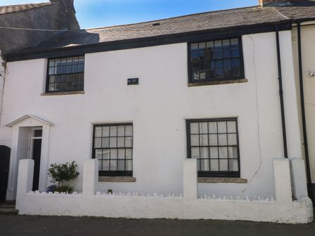 A white cottage with black window frames and a small garden area at Carew House Cottage in St Day