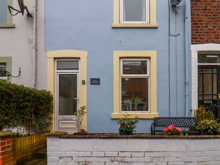 The front exterior of a blue house with a door window bench and potted plants at Sea Fret in Whitby