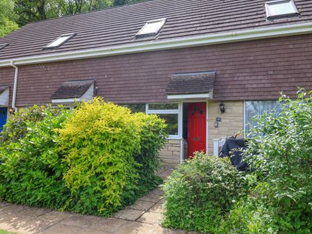 A house with a red door and bushes in front at 50 Fernhill Heights in Charmouth