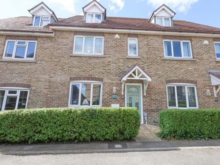 A brick townhouse with multiple windows and green hedges in front at Plain Sailing in Weymouth