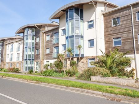Exterior view of a modern apartment building with glass windows wooden panels and landscaping at Apartment 2 in Newquay