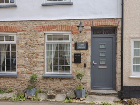 A front view of a cottage with stone walls and windows at Belfry Cottage in Colyton