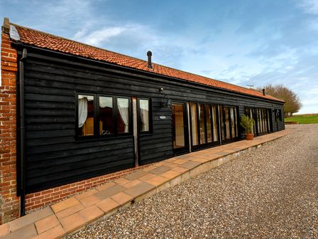An exterior view of a black wooden building with multiple windows and a tiled roof at Pheasant in Wheatacre