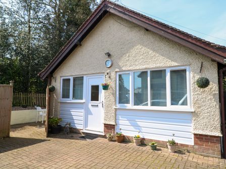 Exterior view of a house with a front door and windows with potted plants on the ground at Paws-A-While in Hoveton & Wroxham