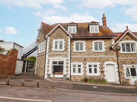 A stone house with white framed windows and a sloped red roof at Sea Haven in Beer