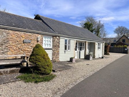 A house with a stone wall and bench at Lighthouse Cottage St Erme near Truro