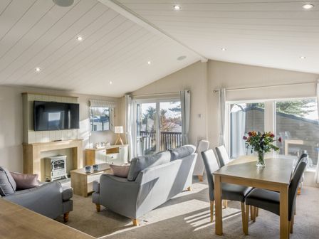 A living room with a sofa and dining table at Lodge 9 at Landscove Holiday Park Brixham