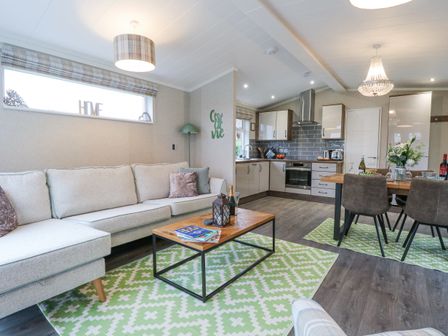 A living room with a sofa and coffee table next to a kitchen and dining table at Wurzburc in Swaffham