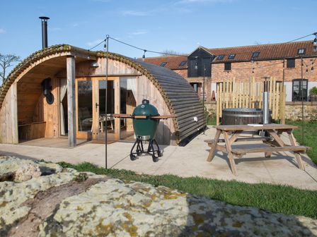 An outdoor area with a wooden glamping pod a green barbecue grill a wooden picnic table and a hot tub at Glamping Pod 3 Harmony in Lebberston