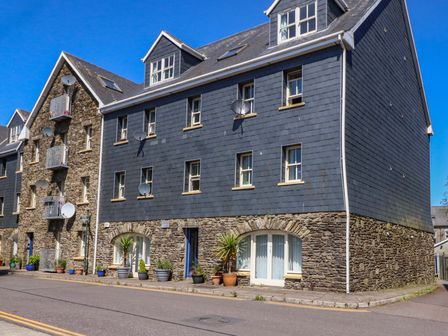 A street view of a building with stone and blue exterior walls with windows and potted plants at 28 Long Quay in Clonakilty County Cork