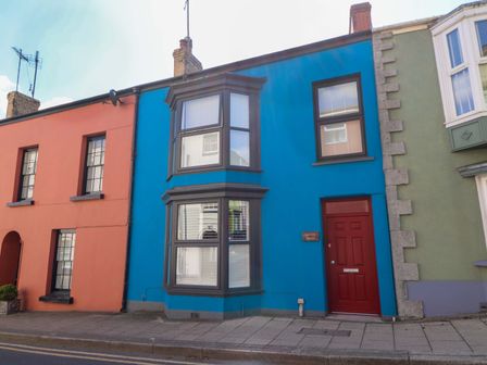 A brightly colored house with a red door at Suffolk House in Narberth
