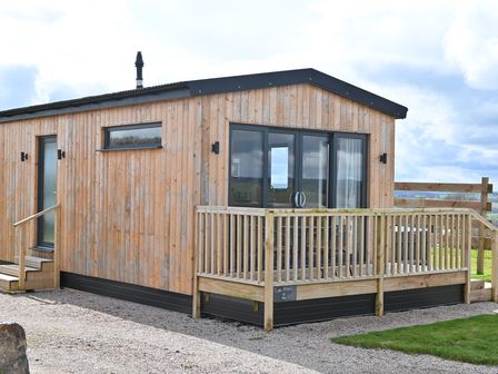 A wooden cabin with a small deck and glass double doors at Cae Dafadd in New Mills near Llanfair Caereinion