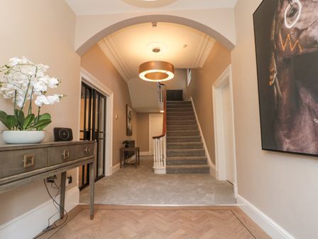 Hallway with carpeted stairs and a wooden console table with a flower pot at Tower View in Scarborough