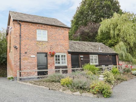 A brick and wood cottage with black doors and windows surrounded by a garden and gravel path at Ramblers in Kerry