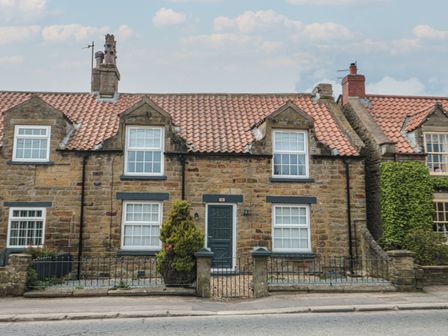 Stone house with tiled roof windows a front door and small fenced garden at 15 High Street in Burniston