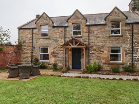 A stone house exterior with a blue front door and outdoor dining set on a patio at Low Moor Loftus near Easington