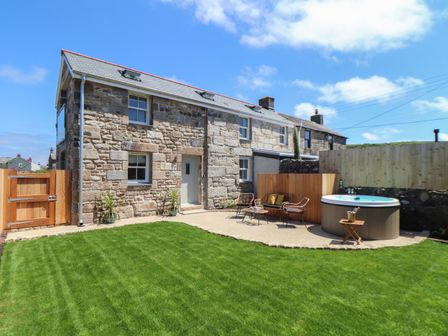 A stone house with a lawn patio seating and a hot tub at Victory View in Pendeen