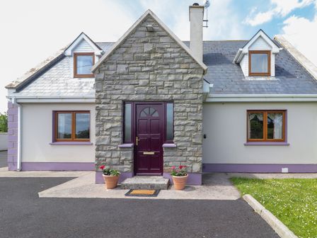 A front view of a house with a stone porch entry and two potted plants at Levally House in Mountrivers Bridge near Doonbeg County Clare