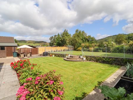 A garden with a lawn flowers and a wooden shed at Craggy View in Staveley