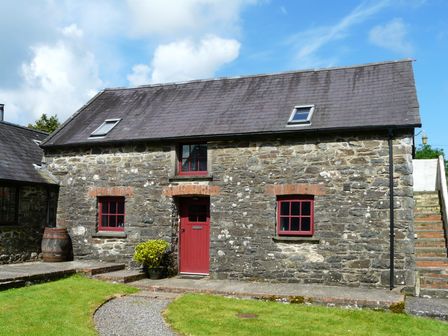 A stone house with red windows and door and stairs on the right at The Old Stable in Pontfaen near Fishguard