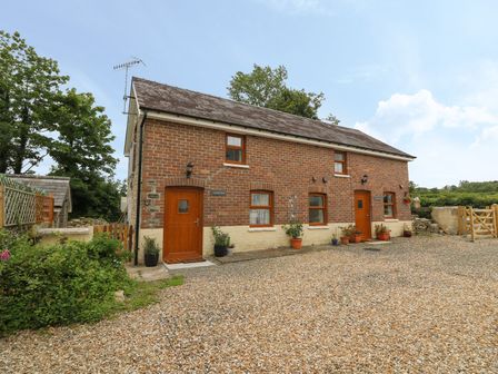 A brick two-door house with potted plants outside and a gravel driveway at Field View in Llanybydder