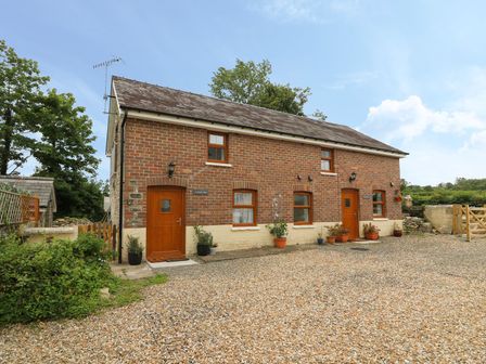 A brick house with two wooden doors and several windows in a rural setting at Garden View in Llanybydder