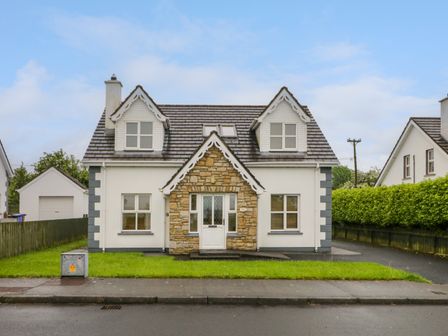 A detached house with dormer windows and a stone entrance facade at 46 Dunalinn in Culdaff County Donegal