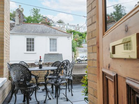 A small patio with metal table and chairs a bottle of wine and two glasses on the table at Albert House in Looe