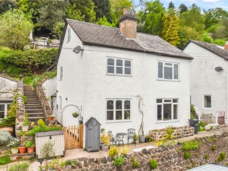 A white two story house with garden furniture and plants outside near stone steps at Holly Cottage in Great Malvern