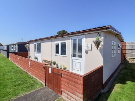 A beige single-story house with white door and windows surrounded by a wooden fence at Sunny South Shore in Bridlington