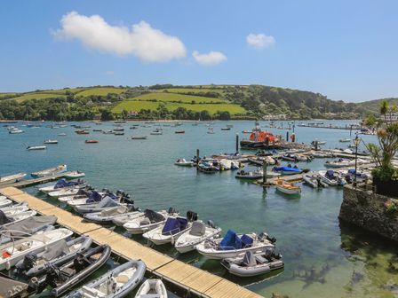 A harbor with boats docked and floating on water with green hills in the background at 7 Island Quay in Salcombe