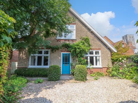 A house with a blue door surrounded by bushes and trees at Samphire House in Southwold