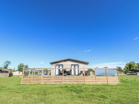 A cabin with a wooden deck and outdoor furniture at Angel Lodge - No 27, Fornham St Genevieve near Bury St Edmunds