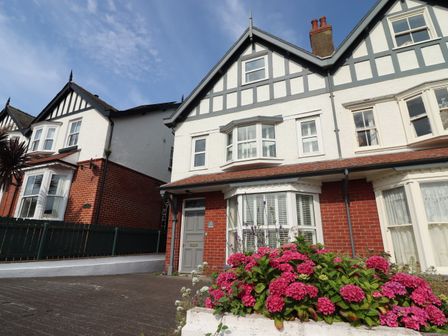 Exterior view of two attached houses with white and red brick walls and flowers in front at Wagtails in Sandsend
