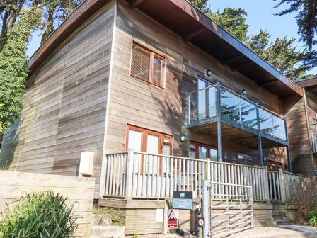 A wooden two-story building with glass balcony and multiple windows at Towan Valley Resort in Porthtowan
