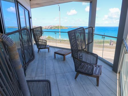 A balcony with four chairs and a small table overlooking the ocean at 17 Cliff Edge in Newquay