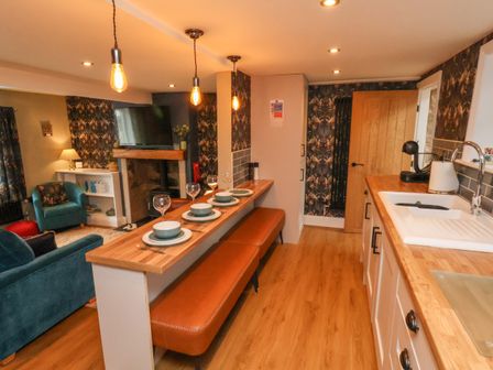 A kitchen and living room with a wooden countertop and bar stools at Seascape Cottage in Marske-by-the-Sea