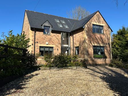 A brick house with a gravel driveway and shrubs in front at Woodside House Woodperry nr Wheatley Oxford