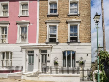 The exterior of two adjacent residential buildings with one painted pink and the other with exposed brickwork in Bournemouth