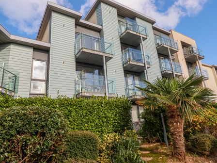 A residential building with glass balconies and greenery in front at 33 Tre Lowen in Newquay