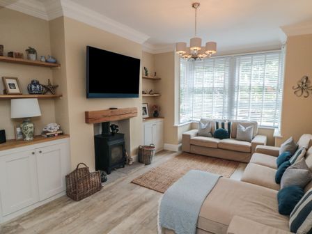 A living room with beige sofas a wall-mounted TV a wood-burning stove and shelves at Thirty Four By the Sea in Scarborough
