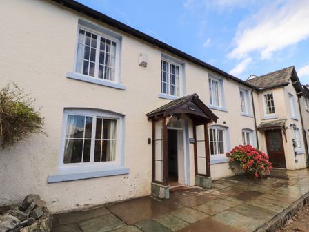 The exterior of a white two-story cottage with multiple windows and a wooden porch entrance at Holborn Cottage Blencathra Street Keswick