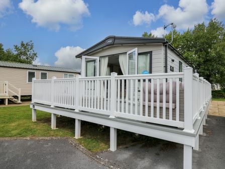 A raised mobile home with white railings and outdoor seating at Osprey 6 in Kiln Park Tenby