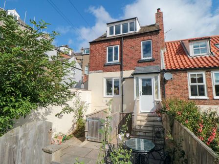 A backyard with patio furniture and garden area attached to a brick and stucco house at 6 Clarence Place in Whitby